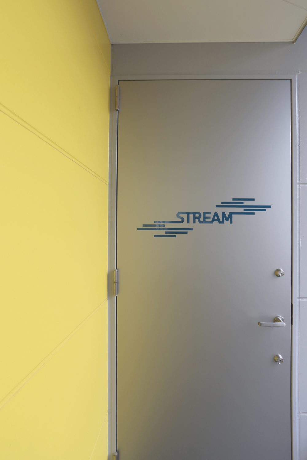 STREAMロゴの入ったシルバーの扉と黄色い壁
